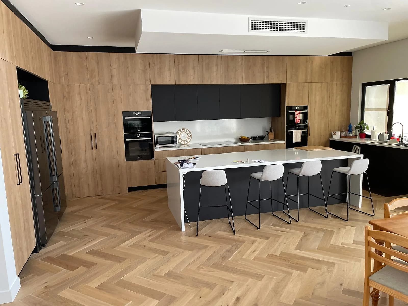 Completed Ryde kitchen with timber cabinetry, charcoal panels and a long island