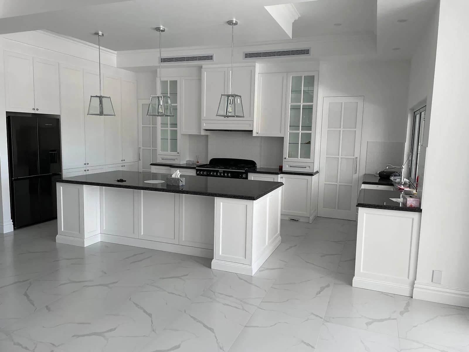 Traditional open-plan kitchen with profiled white cabinetry, dark benchtops and a generous island by H&R Kitchens