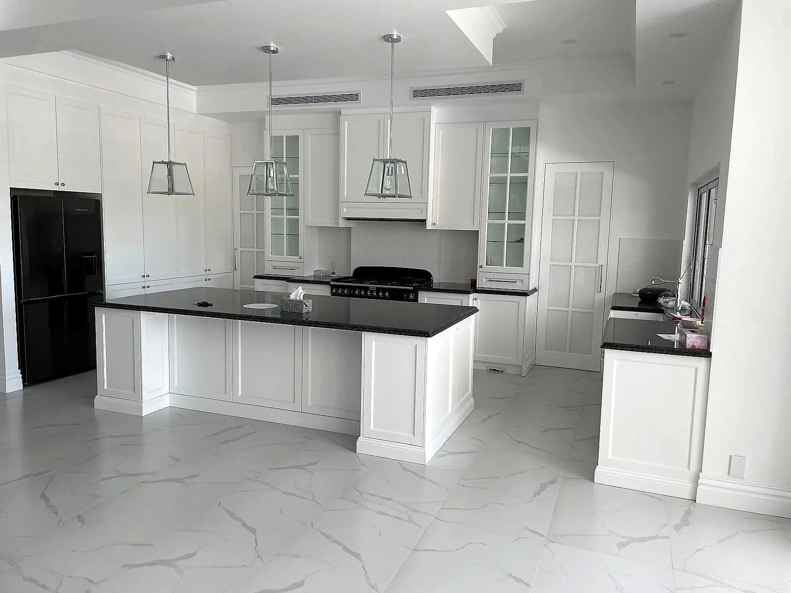 Traditional open-plan kitchen with profiled white cabinetry, dark benchtops and a generous island by H&R Kitchens