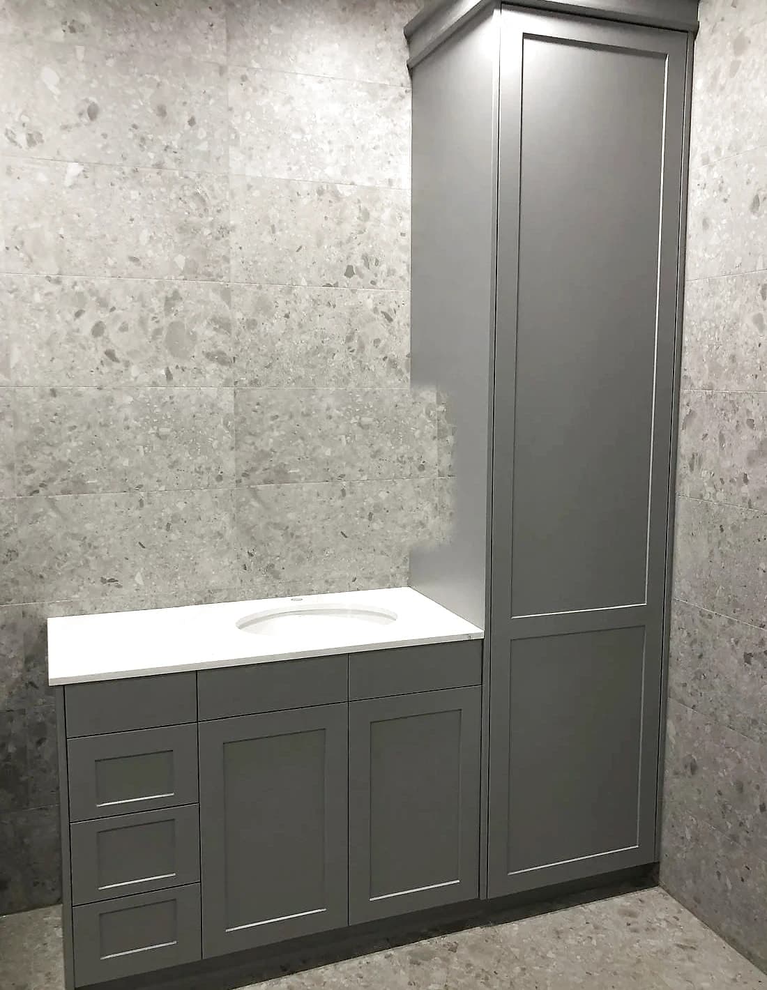 Custom bathroom vanity with grey shaker drawers and doors, a white benchtop with an undermount basin and a matching floor-to-ceiling cabinet, by H&R Kitchens