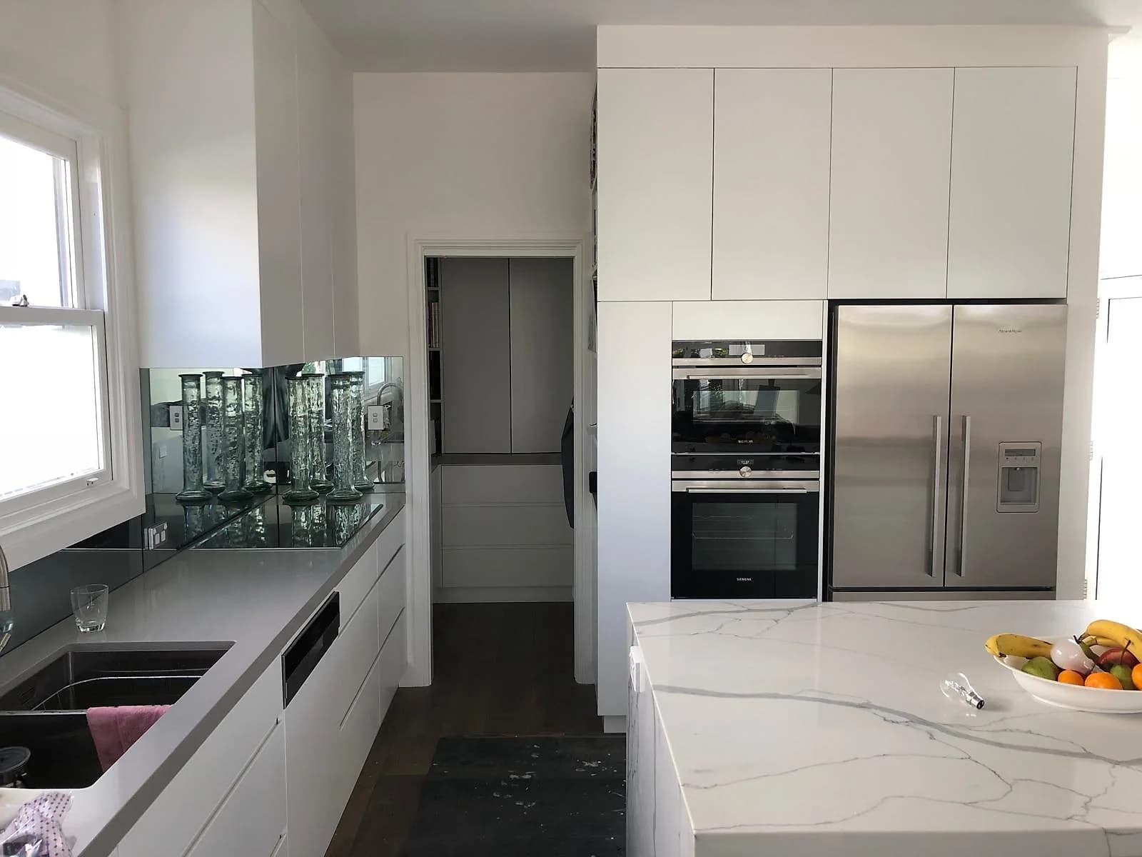 Completed white kitchen with a marble-look island and integrated appliances