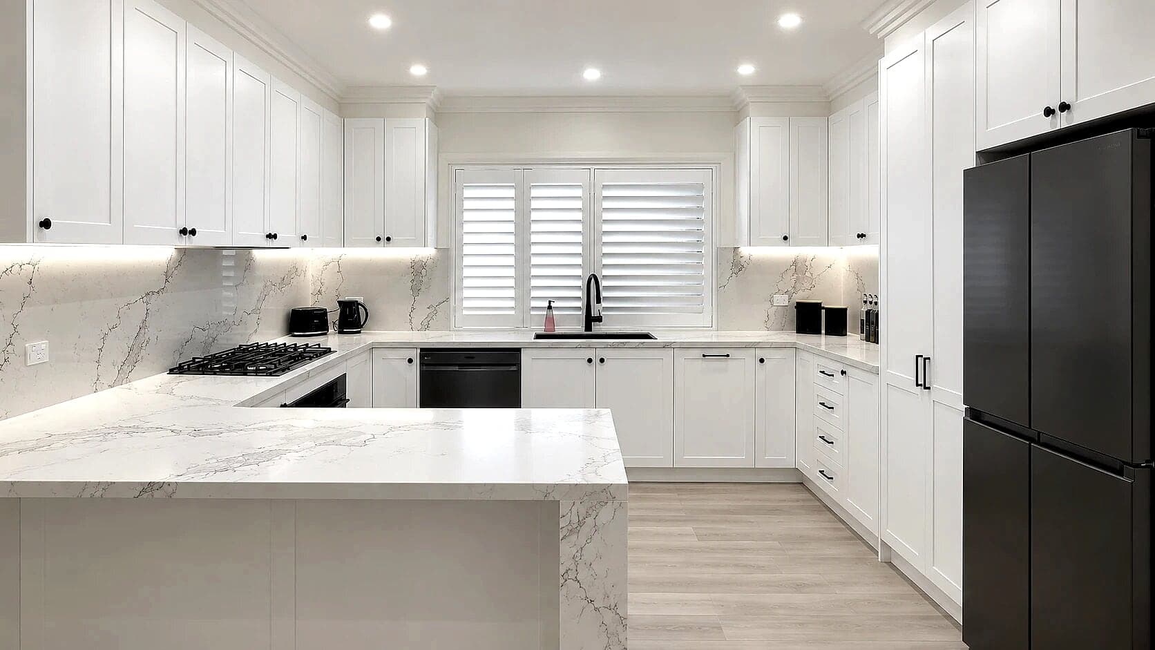 White shaker kitchen in Guildford with a waterfall marble-look peninsula by H&R Kitchens